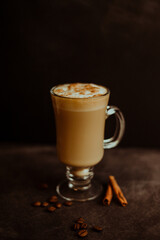 Café expresso com leite, canela e espuma em fundo escuro