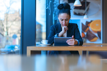 Startup Diversity Brainstorming  Concept. Pretty young Business woman  reading results of  Economy Report Document Laptop.Drinking coffe while wokring inside modern cafe bar.