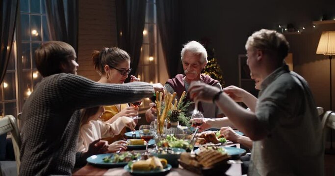 Happy large caucasian family of different generations celebrating christmas at home. People having a dinner xmas party eating, talking and smiling 4k footage