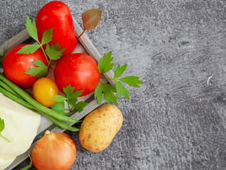 Fresh vegetables on a conc
Fresh vegetables on a concrete background: red tomatoes, green beans, leustean leaves, potatoes and white cabbage on the left and space for text on the right side, top view.
