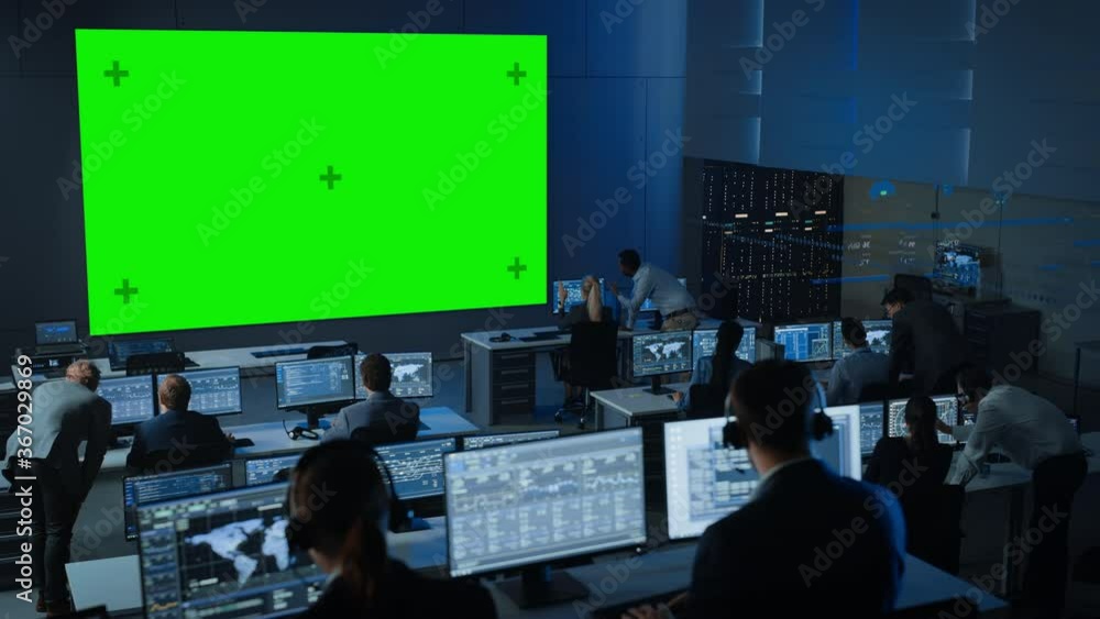 Poster Big Green Screen Horizontal Mock Up in a Control Center Room with Engineers and Controllers Working on Computers. Team of Telecommunication Employees Work in Monitoring Room Full of Displays.