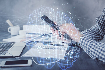 Double exposure of man's hand holding and using a digital device and brain hologram drawing. Data concept.