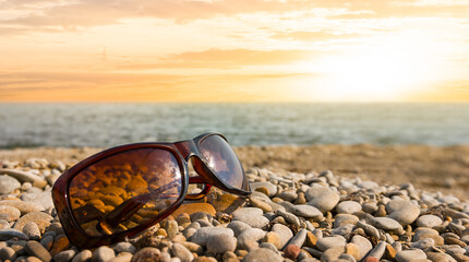 closeup sunglasses lie on a stony sea beach at the sunset