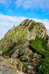 日本国内9番目の標高の名峰、北アルプスの北穂高岳(3106m)から、17番目の南岳（3,033m)、8番目の槍ヶ岳（3,180m）へと続く、三大キレットの一つ、アルピニスト憧れのコース、信州山のグレーディング表で最難関と判定されている「大キレット」の難所、【長谷川ピーク（2,841m)】。夏空、雲、雲海、ヘルメット姿の登山者。夏山。最難関。山岳遭難。縦写真。