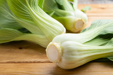 Fresh green bok choy or pac choi chinese cabbage on a brown wooden background. Side view.