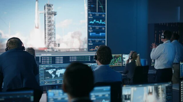 Group of People in Mission Control Center Witness Successful Space Rocket Launch. Flight Control Employees Sit in Front Computer Displays and Monitor the Crewed Mission. Team Stand Up and Clap Hands.
