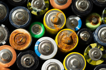 Close up of positive ends of discharged batteries of different sizes and formats, selective focus. Used battery with corrosion and rust. Hazardous garbage concept