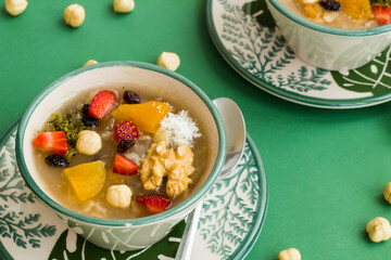 Traditional Turkish Dessert Ashure or Noah's Pudding in stylish bowls on green background with...
