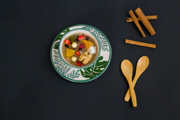 Traditional Turkish Dessert Ashure or Noah's Pudding in stylish green bowls on green background with spoon	