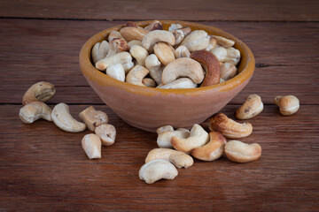 Tasty cashew nuts in bowl on wooden table. Space for text