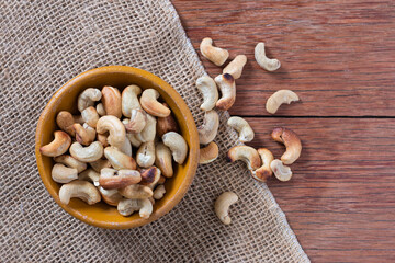 Tasty cashew nuts in bowl on wooden table. Space for text. Top view.