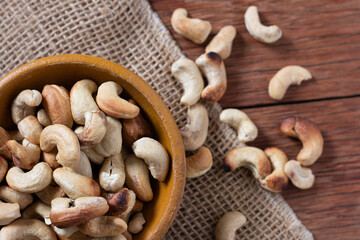 Tasty cashew nuts in bowl on wooden table. Space for text. Top view.