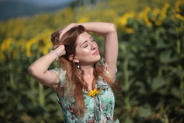 Beautiful young woman in a field of sunflowers in a green dress