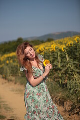 Beautiful young woman in a field of sunflowers in a green dress