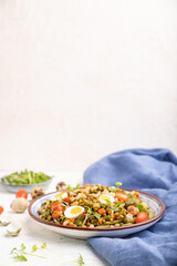 Mung bean porridge with quail eggs, tomatoes and microgreen sprouts on a white concrete background. Side view, selective focus, copy space.