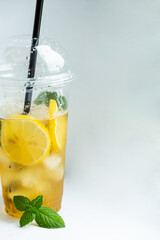 Green tea with iced lemon and lemon balm in a plastic glass on a white background