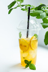 Green tea with iced lemon and lemon balm in a plastic glass on a white background
