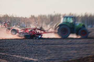 Tractor with a disc harrow system harrows the cultivated farm field, process of harrowing and...