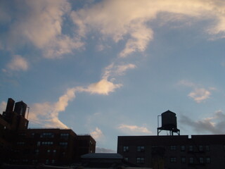 Clouds resembling hands touching over New York City rooftops