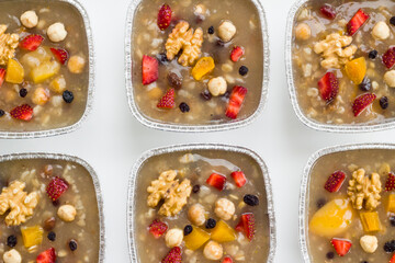 Traditional Turkish Dessert is Noah's Pudding,Asure in foil containers ,take away package,on the white surface with copy space.