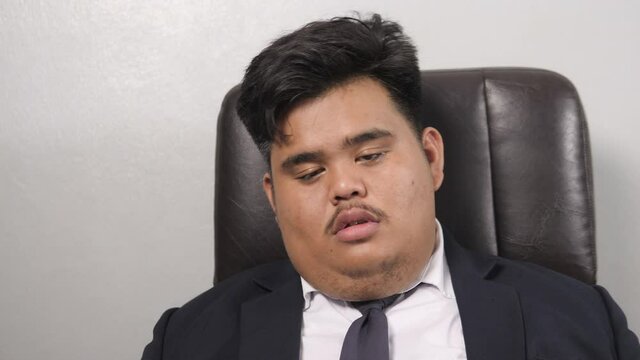A funny Asian fat business man wearing a suit like the head of corporate executive  are sitting and sleeping because of insufficient rest, maybe because of working too hard or sleeping too late.