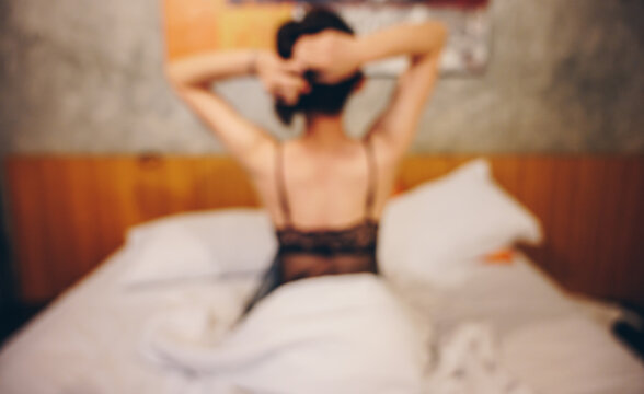 Abstract of blurred background image (defocus) of Prostitution woman sitting on the bed in hotel waiting for her customer.