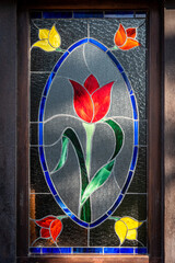 Beautiful stained glass shaping a tulip in several colours, illuminated by sun rays