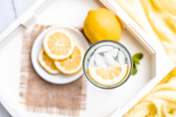 Cold Detox Water with lemon slices and mint on a white wood table 