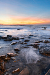 Fototapeta na wymiar Water flowing between rocks with warm sunrise sky.