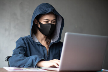 Professional hacker women Wearing a blue shirt with a hood Stealing data from online computer...