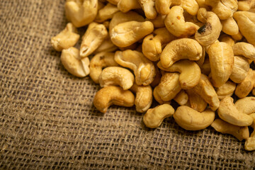 A pile of cashew nuts on burlap with a rough texture surface texture. Close up.