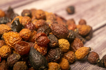 Dried rosehip fruits scattered on a wooden background. Close up.