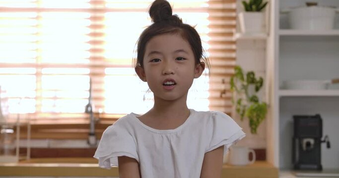 Close up portrait of cute little kid making videocall or vlog. Happy asian child girl talking and laughing looking at web cam during communicate in online chat. webcam view, videochat concept.