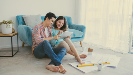 Obraz premium close up of happy couple looking at blueprint at home
