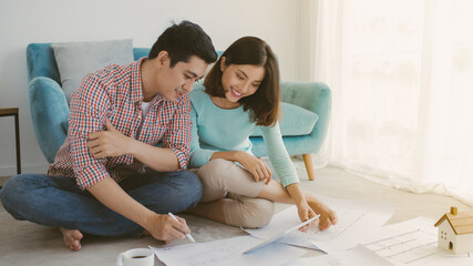 Couple standing by the table and looking at blueprints for their house.