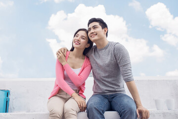 Love on the roof. A young Asian couple sitting together.