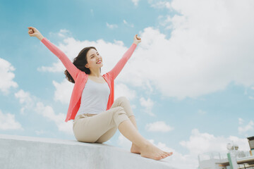 Beautiful young Asian woman sitting on the rooftop.