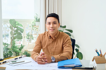 Portrait of young Asian architect man woking with blueprint at his office