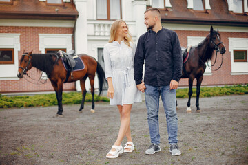 Couple in a summer rainy park. Pair standing with a horse. Girl in a white dress
