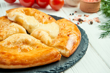 Close up view on tasty traditional Khachapuri - closed baked pie stuffed with melted salt cheese (suluguni). georgian food