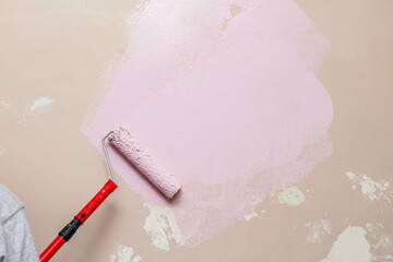 painting wall with a roller in pink color