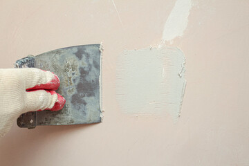 Puttying, sealing cracks with gypsum plaster using a spatula. Damaged wall repair.