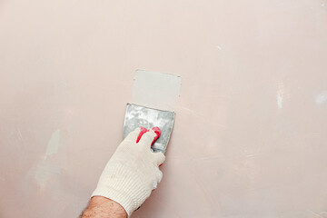 Puttying, sealing cracks with gypsum plaster using a spatula. Damaged wall repair.