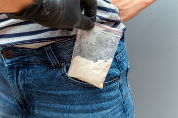 Drugs packet found in pocket during a police search with hand in black glove