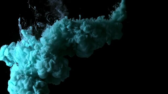 Teal blue fluid pearl inks are exploding and creating beautiful colorful cloud. Slow motion of turquoise paint isolated on black background. Creative abstract art for beauty business background.