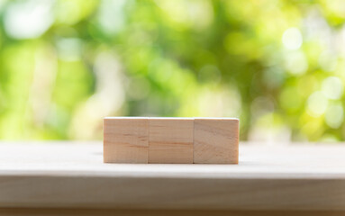 Wood cube over  nature green blurred background