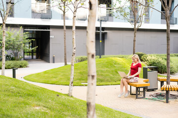 Euphoric woman searching job with a laptop in an urban park in summer
