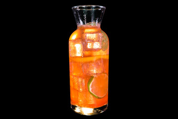 Fresh lemonade with strawberry and lemon in a transparent bottle with ice with reflection, isolated on black background