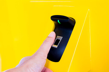 Finger biometric scanner with blurry finger on yellow machine. The concept data access control with fingerprint system.