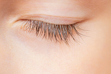 Close up of one closed eye with natural long eyelashes of young girl with perfect healthy skin....